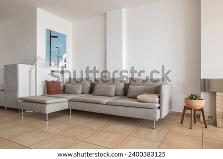 Corner sofa with cushions and picture in smart apartment
