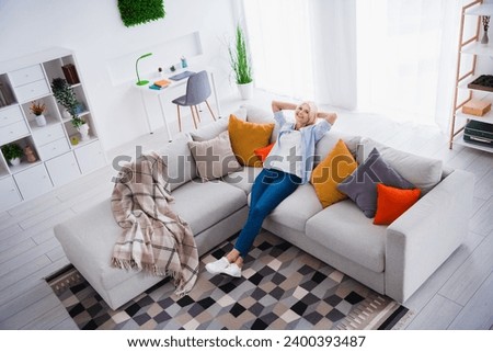 Photo portrait of lovely senior lady hands behind head dreamy enjoy weekend house interior design cozy living room modern home decor