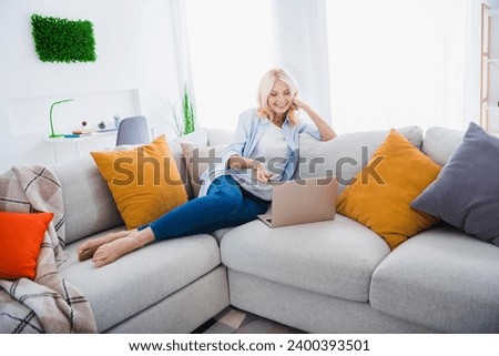 Photo portrait of charming retired woman sit sofa communicate video call netbook weekend stylish home decor living room modern apartment