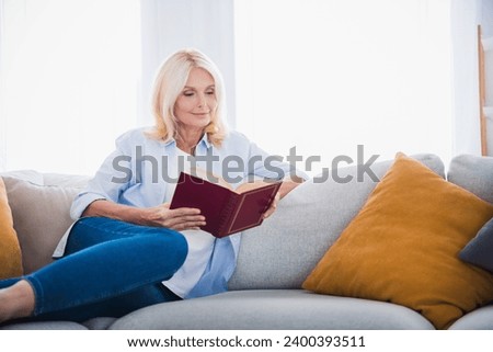 Photo portrait of attractive pensioner woman sitting sofa hold book reading enjoy morning living room modern interior decoration