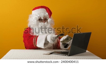 Santa Claus with money dollars and laptop.