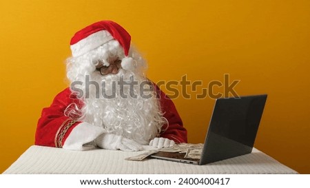 Santa Claus with money dollars and laptop.