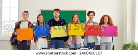Group of cheerful school, college or university students with colorful paper banners. Happy smiling optimistic young people standing in row holding orange, blue, yellow, red and pink mockup posters
