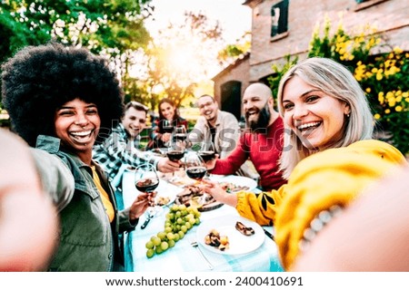 Group of multiracial friends taking selfie at barbecue dinner time - Young people relaxing outdoors eating and drinking red wine in restaurant garden - Concept of food, youth friendship and holidays