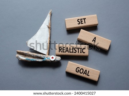 Set a realistic goal symbol. Concept words Set a realistic goal on wooden blocks. Beautiful grey background with boat. Business and Set a realistic goal concept. Copy space.