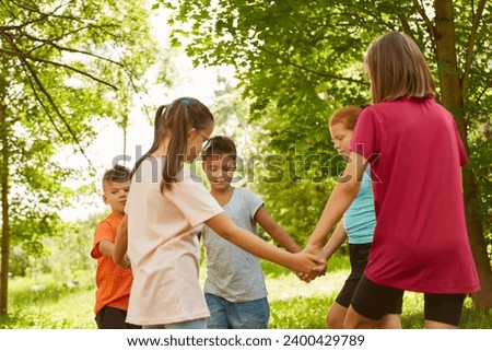Male and female friends enjoying while playing ring-around-the-rosy at park Royalty-Free Stock Photo #2400429789