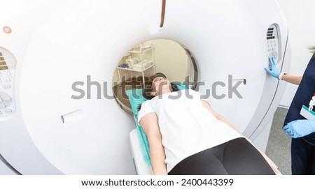Pretty, young woman goiing through a Computerized Axial Tomography CAT Scan medical test examination in a modern hospital Royalty-Free Stock Photo #2400443399