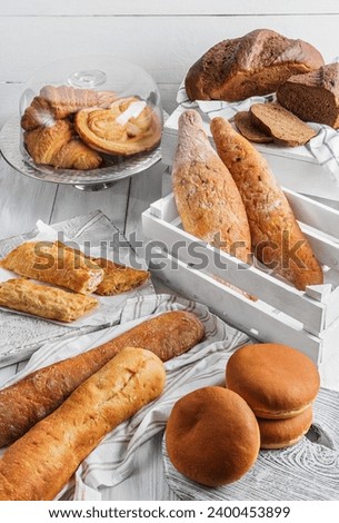 Assortment of various delicious freshly baked bread on white wooden background. Vertuta, stuffed bread, pastries, croissants, strudel, baguette, buns. Homemade healthy bread, grocery store, top view