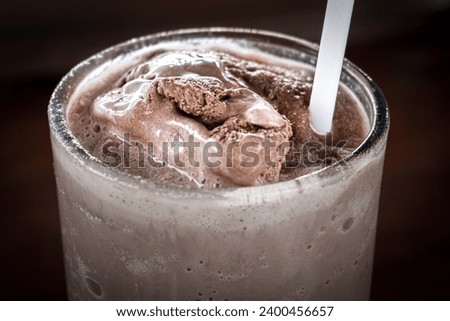 Glass of chocolate milkshake on wooden table