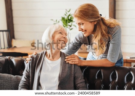 Middle aged nurse taking care of old woman indoors. Caregiver caretaker carer medical worker visiting grandmother senior patient with mental issues dementia in hospice Royalty-Free Stock Photo #2400458589