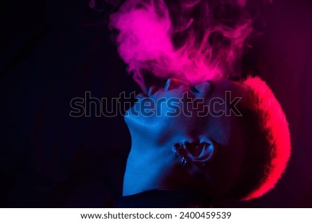Profile Asian woman with short haircut smoking in neon light.
