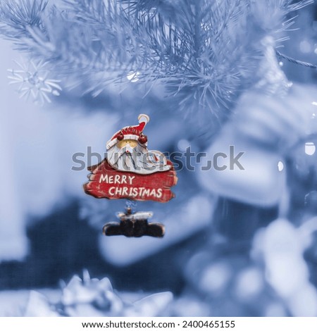 Old handmade wooden toy Santa Claus on the Christmas tree and lights at blurred background.