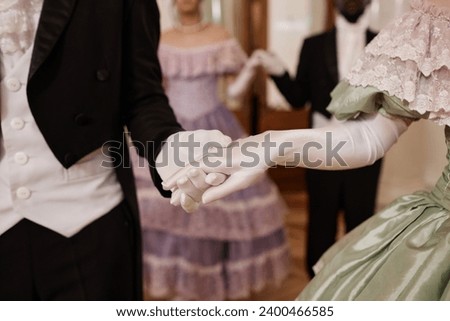 Close up of unrecognizable lady and gentleman holding hands wearing gloves entering ballroom together, copy space Royalty-Free Stock Photo #2400466585