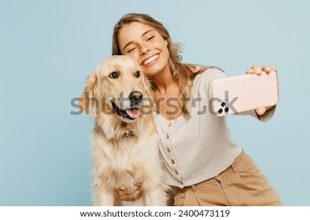 Young happy owner woman with her best friend retriever wear casual clothes do selfie shot on mobile cell phone hug dog isolated on plain pastel light blue background studio Take care about pet concept