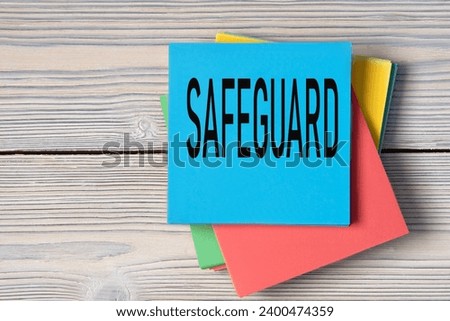 SAFEGUARD - word on note paper on wooden light background. Info concept Royalty-Free Stock Photo #2400474359