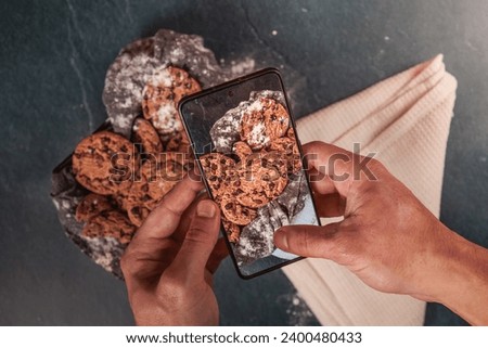 Man hands taking a picture of chocolate cookies to post it in social media.
