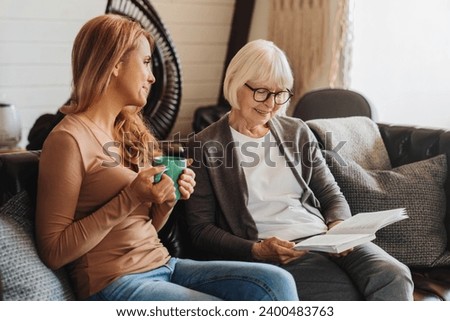 Middle aged woman spending time with her senior mother at home. Family traditions, bonding and togetherness. Grandchildren visiting lonely granny
