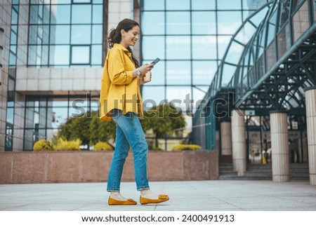 Girl using mobile phone on a city street. Freelance work, communication, business, connection, mobile apps, meeting online, travel concept. Connected city worker. 