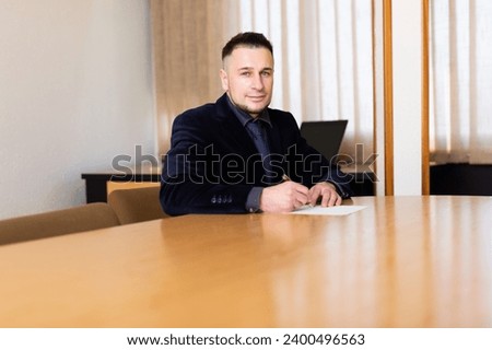 Portrait of positive young adult man at workplace in office