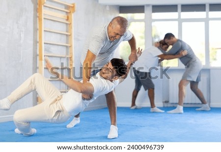 Old man and young guy in group training fight in sparring and apply judo techniques
