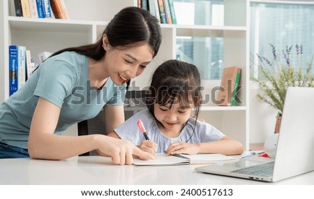 Photo of young Asian mother and daughter studying at home