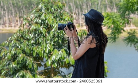 A beautiful woman using a camera during her vacation to capture memories, Beautiful woman taking pictures outdoors.