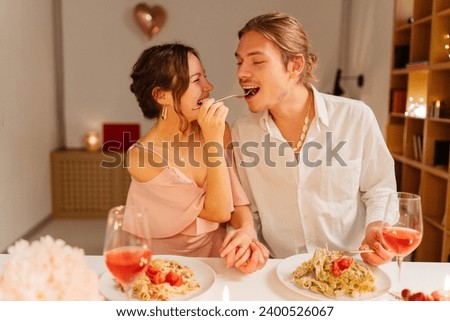 Portrait of happy, smiling young man and woman eating, sitting in restaurant. Attractive romantic couple celebrating birthday. Concept of love, dating