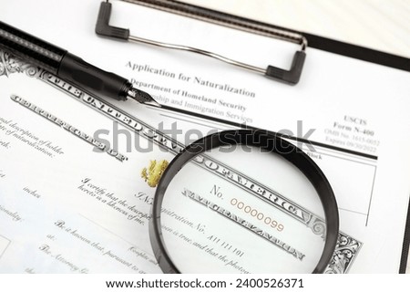 N-400 Application for Naturalization and Certificate of naturalization on A4 tablet lies on office table with pen and magnifying glass close up Royalty-Free Stock Photo #2400526371