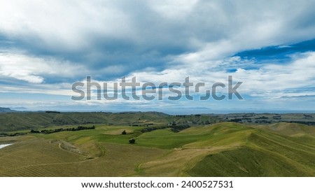The rolling green hills and valleys comprising agricultural and farm countryside Royalty-Free Stock Photo #2400527531