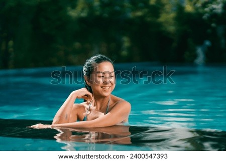 Young asian woman relaxing in the water, Beautiful girl relaxing at overwater infinity pool luxury resort. Spa, wellness, swimming.	
