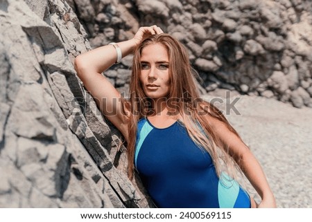 Woman summer travel sea. Happy tourist in blue bikini enjoy taking picture outdoors for memories. Woman traveler posing on the beach surrounded by volcanic mountains, sharing travel adventure journey