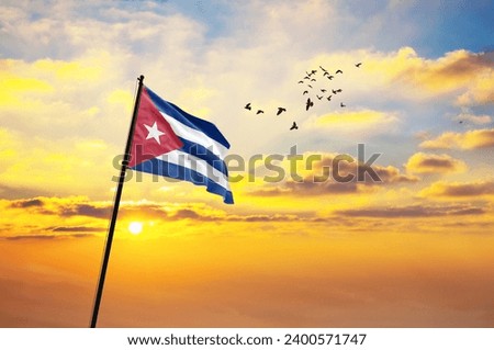 Waving flag of Cuba against the background of a sunset or sunrise. Cuba flag for Independence Day. The symbol of the state on wavy fabric.