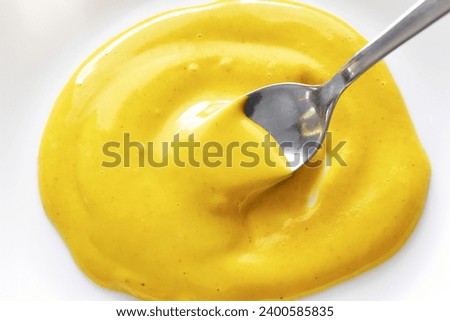 Yellow mustard on a spoon. Cooking preparation concept. Royalty-Free Stock Photo #2400585835