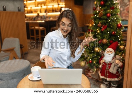 Young woman sitting in the restaurant and having a video call on laptop. Female professionals video calling on laptop sitting at cafe.