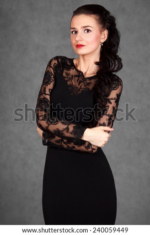 Portrait of a young attractive woman in a black evening dress over grey background