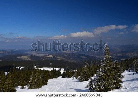  Spring mountain panorama with snow-covered slopes and green valleys