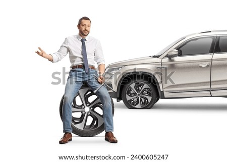Unhappy man with a SUV sitting on a car tire and holding a lug wrench isolated on white background