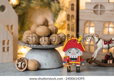 A toy soldier Nutcracker and walnuts on a Christmas background with a garland. Tchaikovsky's ballet. Christmas New Year card 2024.