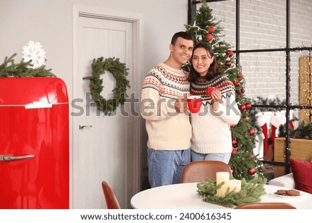 Young couple drinking hot cocoa in kitchen on Christmas eve