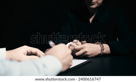 An arrested crime suspect in handcuffs is testifying to a police detective, confessing Royalty-Free Stock Photo #2400616747