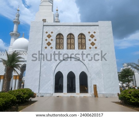 The large building of the Syech Zayed Solo Mosque looks clear against the sky and trees in the mosque yard  Royalty-Free Stock Photo #2400620317