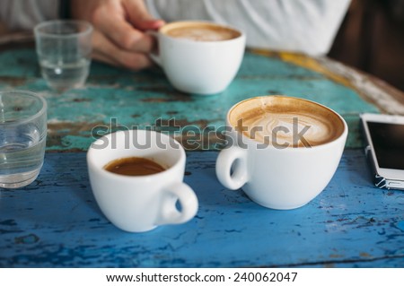 People talking in the cafe while having some fresh coffee (two cappuccinos and one espresso with beautiful tiger crema) Royalty-Free Stock Photo #240062047