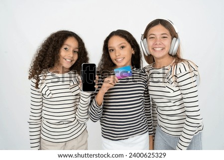Photo of adorable multi racial group of girl friends holding credit card and Smartphone. Reserved for online purchases