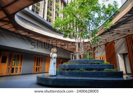 Luxurious Thai resort, woman on solace in the gentle morning sun. Architecture and nature blend, ultimate relaxation.