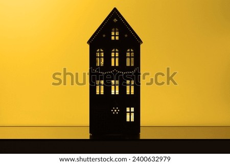 Decorative object, Christmas house with glowing windows, yellow background for text, magical mood
