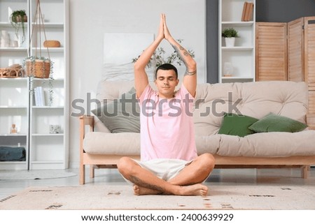 Young man doing yoga on carpet at home