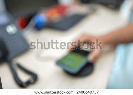 Royalty high quality free stock photo a man hand holding his smart phone on wireless charger adapter. View in the office desk.