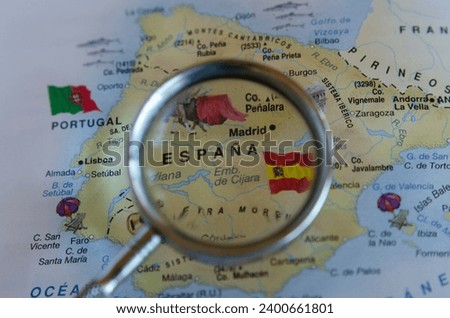 map of spain put in a magnifying glass with its flag flying and view of its capital madrid