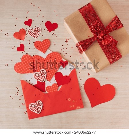 Creative pattern of envelope, gift box and red paper hearts. Concept for Valentine's Day. Flat lay.
