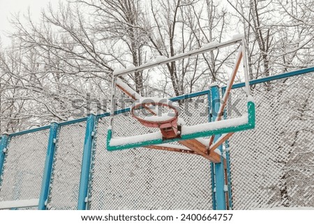 An old basketball hoop is covered with snow. The first snow in the city